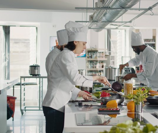 chef-feminin-cuisinant-un-plat-de-gastronomie-avec-des-legumes-sur-la-cuisiniere